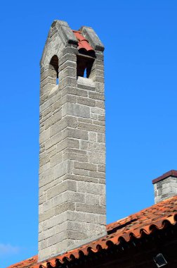 Evin arka planında eski bir baca var.