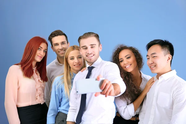 Jovens Fazendo Foto Grupo Com Telefone Inteligente Fundo Parede Azul — Fotografia de Stock