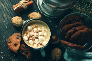 Hatmi ve siyah masada kurabiye ile sıcak kakao bir fincan