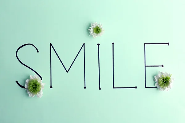 Inscription smile with white flowers — Stock Photo, Image