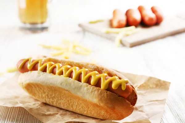 Hot dog με τηγανητές πατάτες σε χαρτί βιοτεχνίας σε φόντο ξύλινη — Φωτογραφία Αρχείου