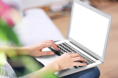 Kanepede dizüstü bilgisayarlı bir kadın oturuyor. 