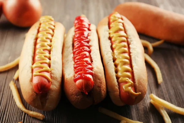 Cachorros-quentes com batatas fritas no fundo de madeira — Fotografia de Stock