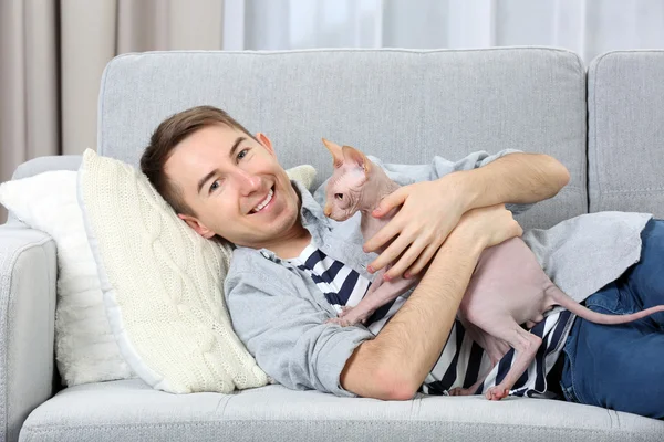 Hombre guapo se acuesta con gato en el sofá — Foto de Stock