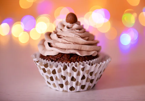 Cupcake de chocolate saboroso com creme de manteiga em um fundo de brilho, close-up — Fotografia de Stock