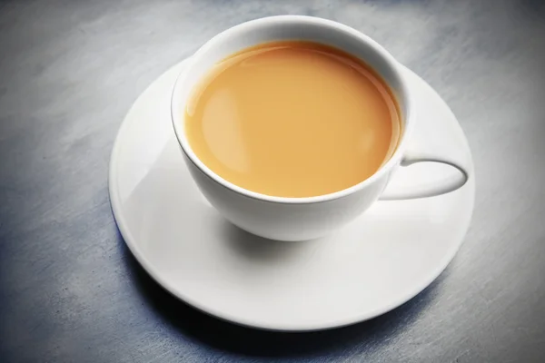 Порцелянова чашка чаю з молоком на сірому фоні — стокове фото