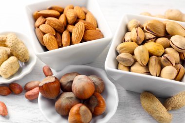 Antep fıstığı, badem, fındık, fıstık ve ceviz badem Beyaz ahşap arka plan üzerinde seramik kase