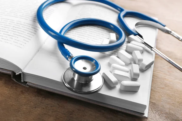 Stethoscope with pills and book — Stock Photo, Image