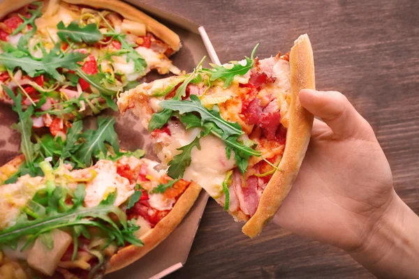 Piece of fresh pizza in hand — Stock Photo, Image