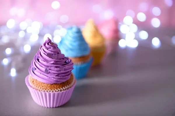 Cupcake with purple cream icing on a glitter background, close up — Stock Photo, Image