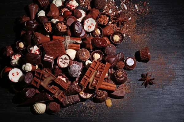 다양 한 맛 있는 초콜릿 사탕, 계 피 나무 테이블 배경 — 스톡 사진