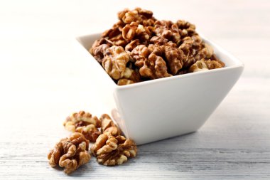 Beyaz ahşap zemin üzerinde kapta ceviz taneleri