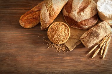 Taze pişmiş ekmek ve bir kase ahşap arka plan üzerinde buğday tanelerinin