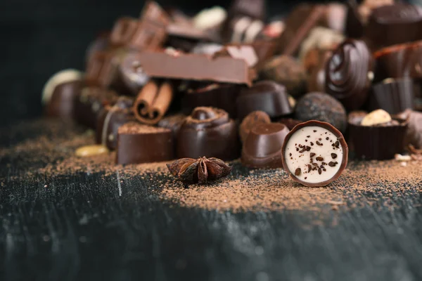 Surtido de sabrosos caramelos de chocolate y canela sobre fondo de mesa de madera — Foto de Stock