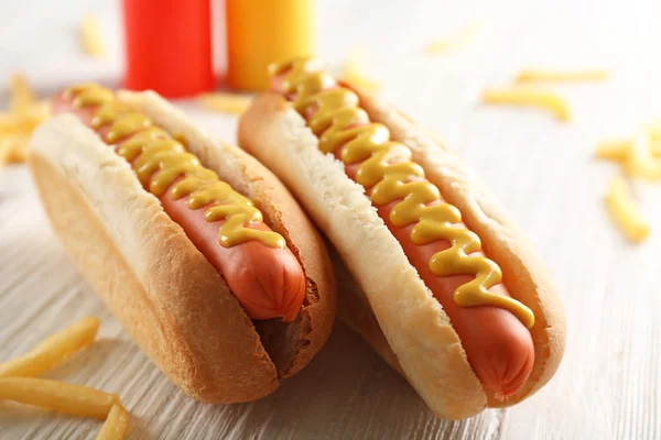 Perros calientes y papas fritas sobre fondo de madera —  Fotos de Stock