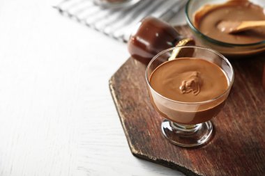 Ahşap arka plan üzerinde cam kapta eritilmiş çikolata