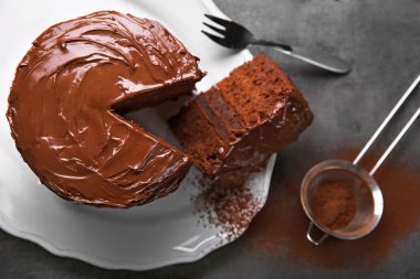 Plaka kesme parça ve çatal ve gri arka plan, closeup üzerine kakao ile çikolatalı kek