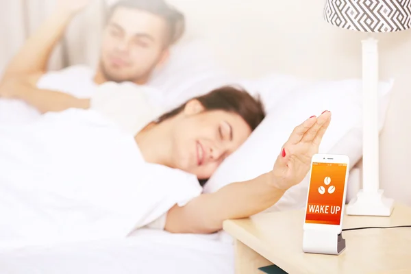 Casal acordar com despertador móvel — Fotografia de Stock