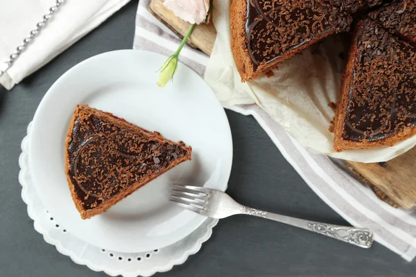 Bolo de chocolate fatiado na placa, no fundo da mesa de madeira — Fotografia de Stock