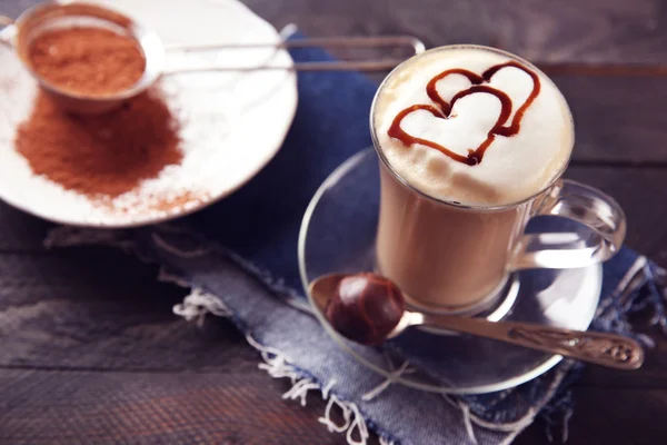 Milchkaffee in Glasbecher mit Schokoladensirup auf schwarzem Holztisch — Stockfoto