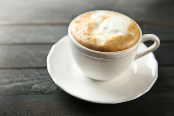 Kopje warme cappuccino met schuim op een zwarte houten tafel — Stockfoto