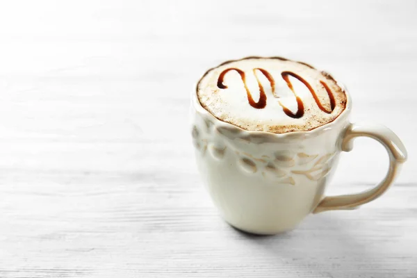 Copa de capuchino con jarabe de chocolate sobre mesa de madera clara —  Fotos de Stock