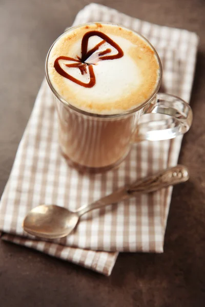 Milchkaffee in Glasbecher mit Schokoladensirup auf grauem Tisch — Stockfoto