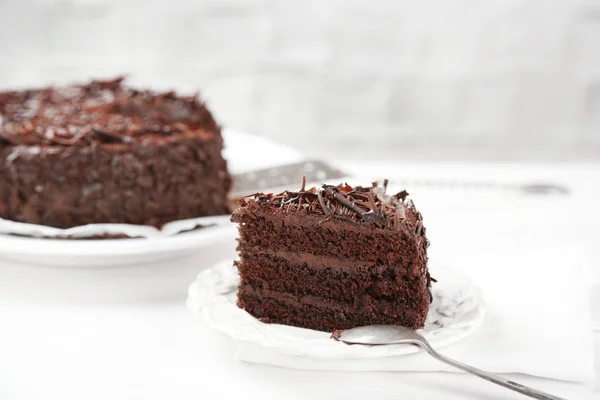 Sliced chocolate cake on wooden table, on light background — Stock Photo, Image