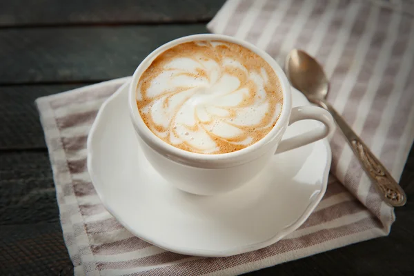Csésze-ból forró cappuccino, tejhab, és kanállal a fekete fából készült asztal — Stock Fotó