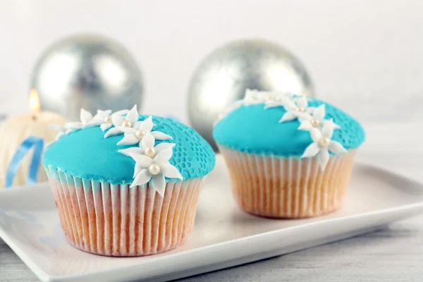 Dos sabrosos cupcakes azules con decoraciones sobre fondo claro — Foto de Stock