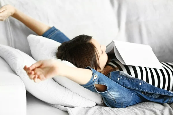 Menina bonita descansa com livro no sofá — Fotografia de Stock