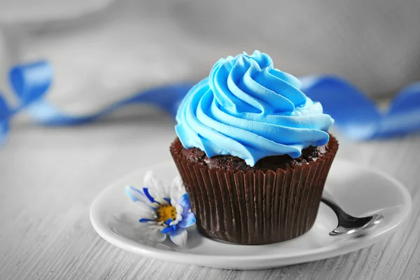 Смачний шоколадний кекс з синім кремом на декорованому дерев'яному столі, крупним планом — стокове фото