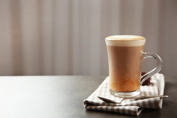 Café con leche en taza de vidrio y cuchara sobre mesa gris — Foto de Stock