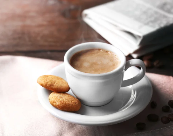 Чашка кофе, печенье и газета на фоне деревянного стола — стоковое фото