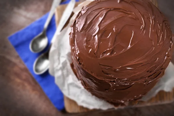 Chocoladetaart met twee lepels en blauw tafelkleed op een houten planken-achtergrond — Stockfoto