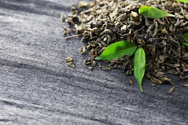 在灰色的背景上绿色的叶子茶颗粒 — 图库照片