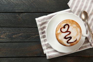 Çikolata şurubu ve bir siyah ahşap masa kaşık ile sıcak cappuccino fincan