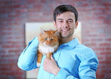 Genç adam kırmızı kedi tutmak gülümseyen