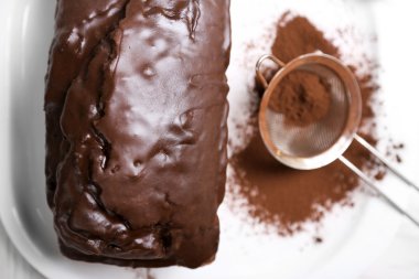 Çikolatalı kek buzlanma ve kakao tozu beyaz masa üzerinde