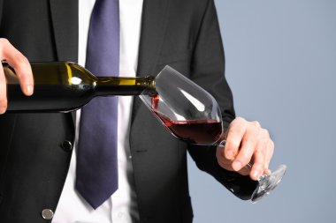 Kırmızı şarap bir bardak dökme takım elbiseli adam