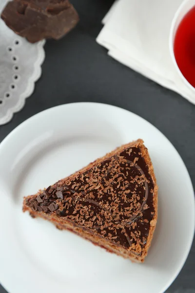 Нарізаний шоколадний торт на тарілці, на дерев'яному фоні столу — стокове фото