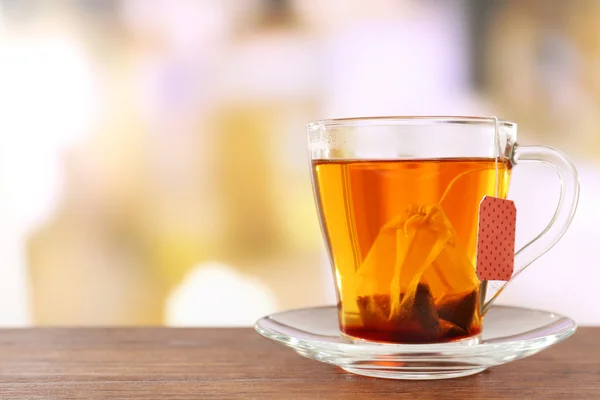 Glass cup with tea bag on wooden table, close up — Stock Photo, Image