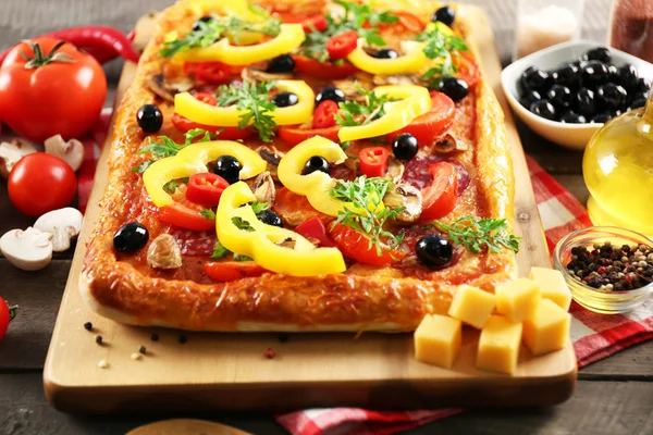 Rechthoek heerlijke pizza en groenten op tafel — Stockfoto