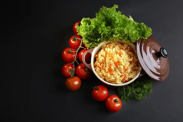 Arroz cozido com uma cenoura e tomates em uma panela de cozinha sobre fundo preto — Fotografia de Stock