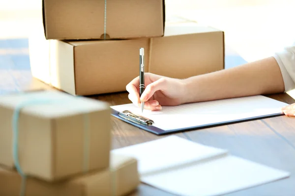 Mujer firma papeles entre paquetes — Foto de Stock