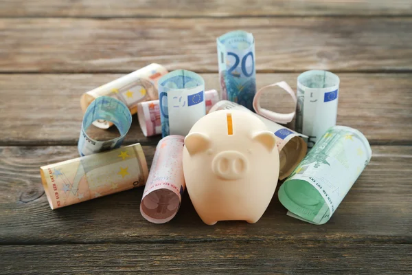 Свинячий банк з рулонними євро банкнотами — стокове фото