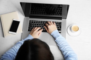 Laptop ile çalışan kadın ahşap masanın üstüne yerleştirilir. Üstten Görünüm