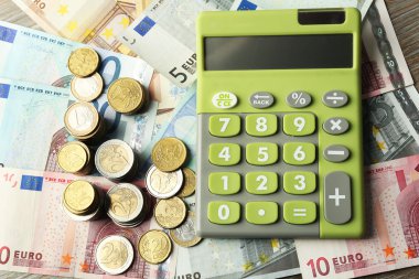 Para kavramı. Yeşil hesap makinesi ile banknot ve madeni paralar, yakın çekim