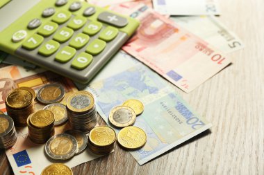 Para kavramı. Yeşil hesap makinesi ile banknot ve madeni paralar, yakın çekim
