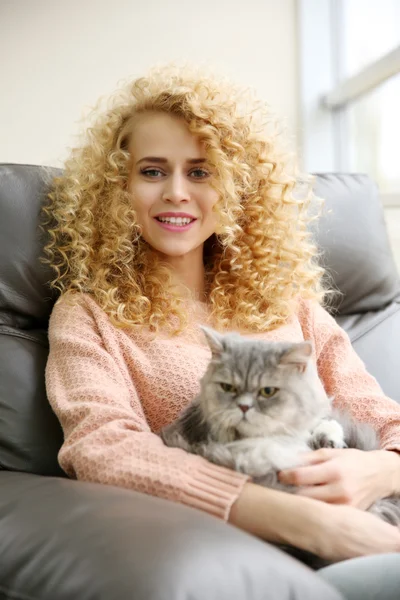 Junge Frau und Katze auf dem Sofa im Zimmer — Stockfoto